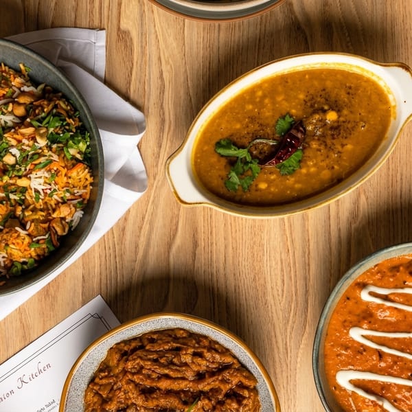 Overhead view of various Indian dishes, including rice, dal, and curries, on a wooden table.